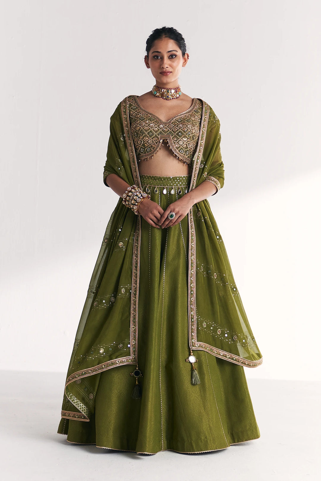Woman wearing a green embroidered traditional Lehenga Set on a white background