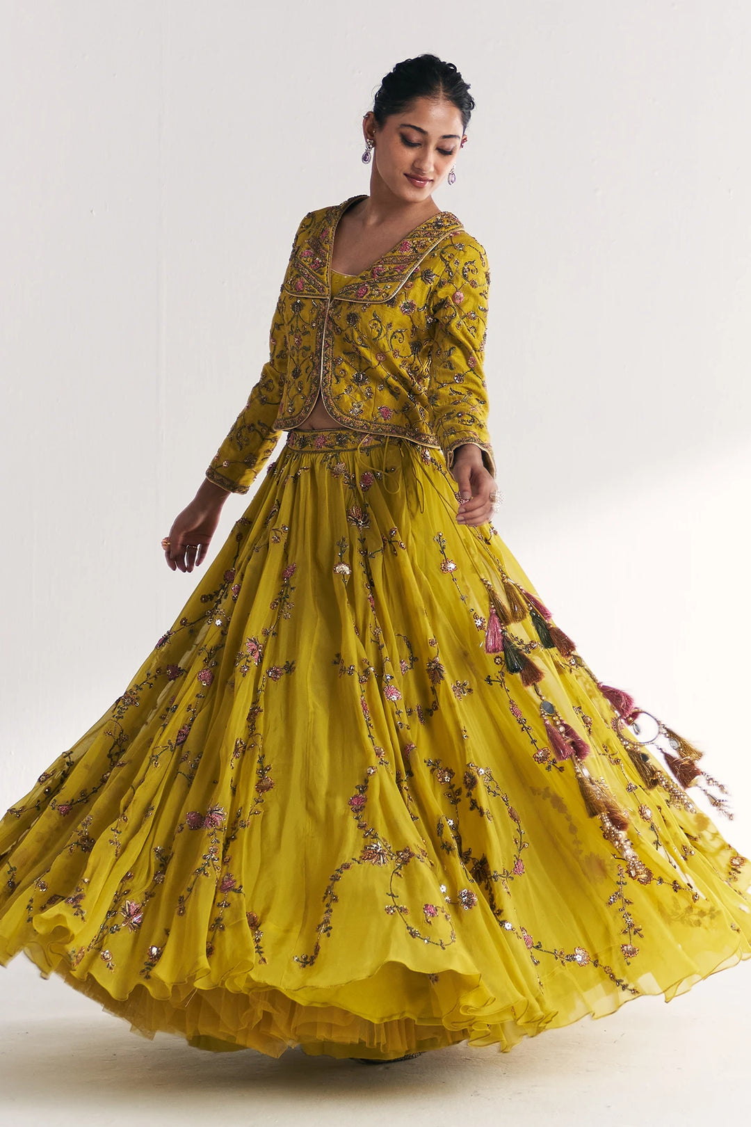 Woman wearing a yellow embroidered traditional Lehenga Set on a white background