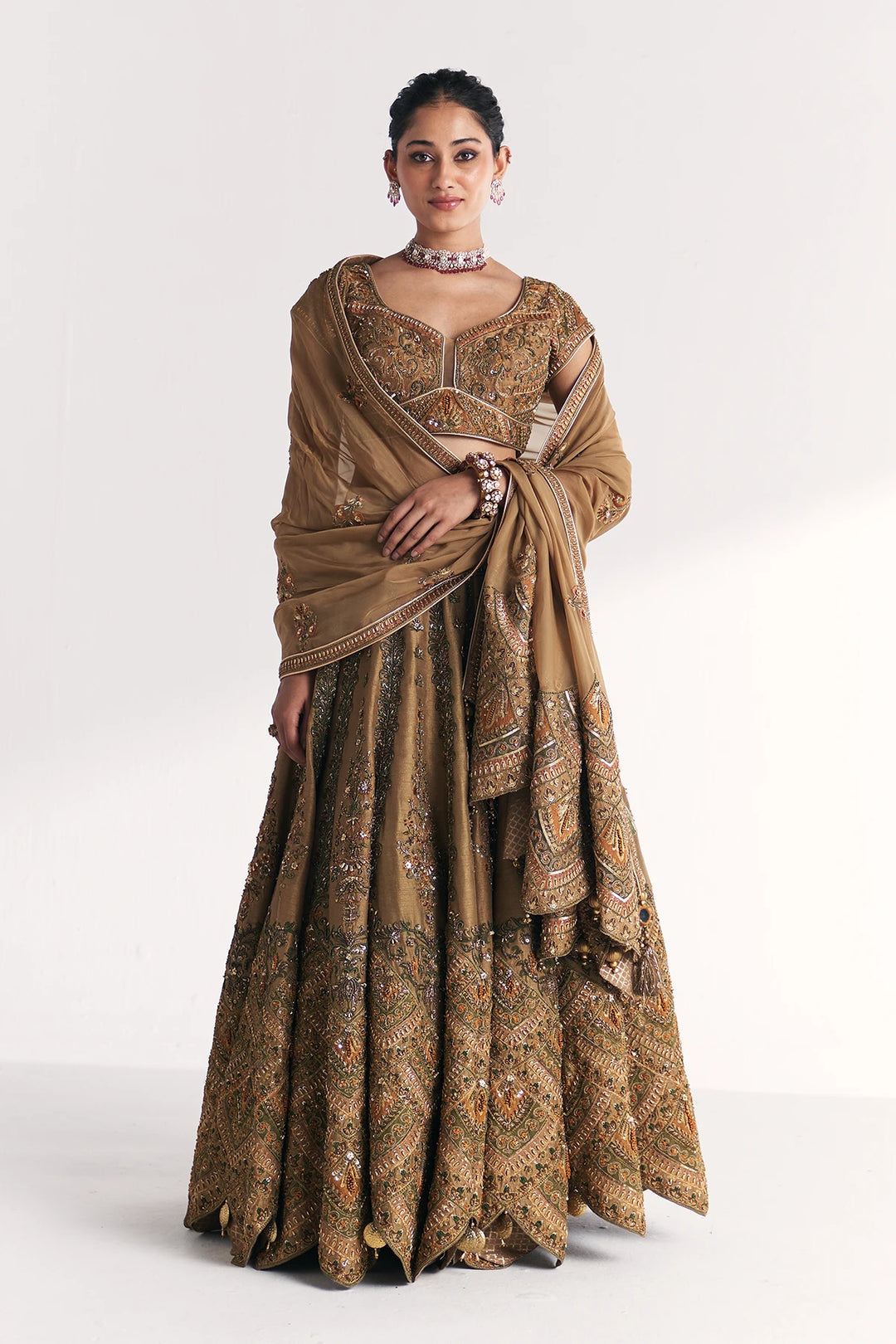 Woman wearing a traditional brown and gold Lehenga Set with a white background