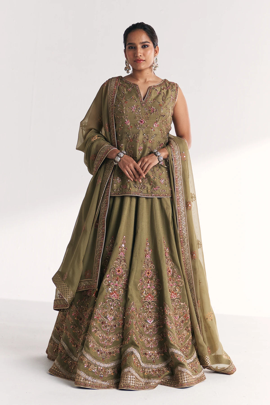 Woman wearing a traditional green embroidered Lehenga Set with a white background