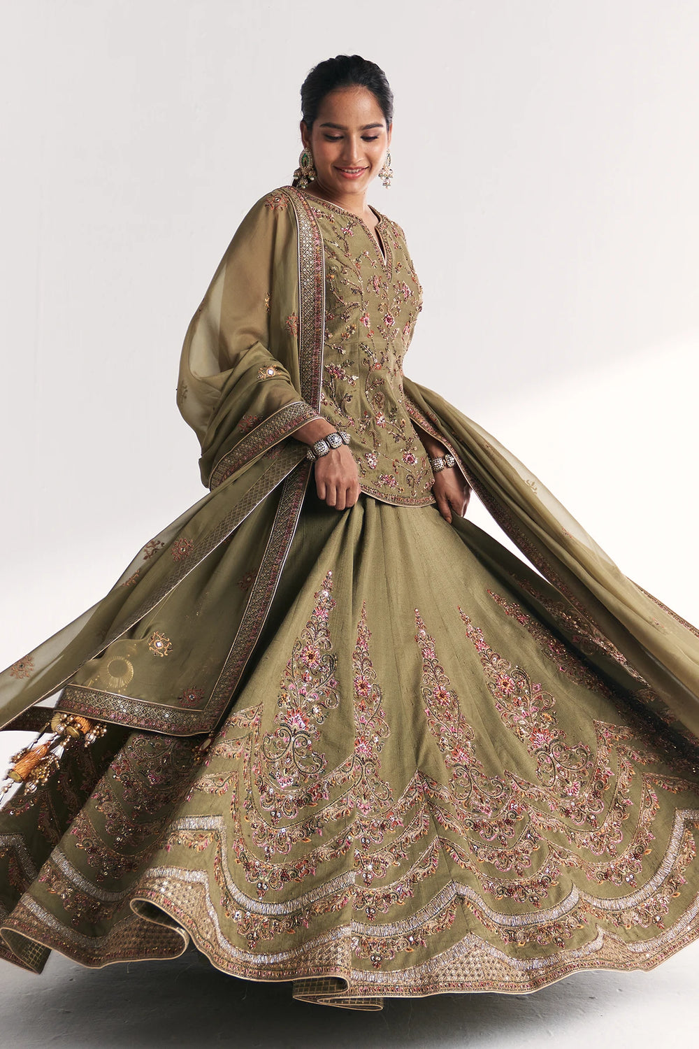 Woman wearing a traditional embroidered green Lehenga Set with a white background
