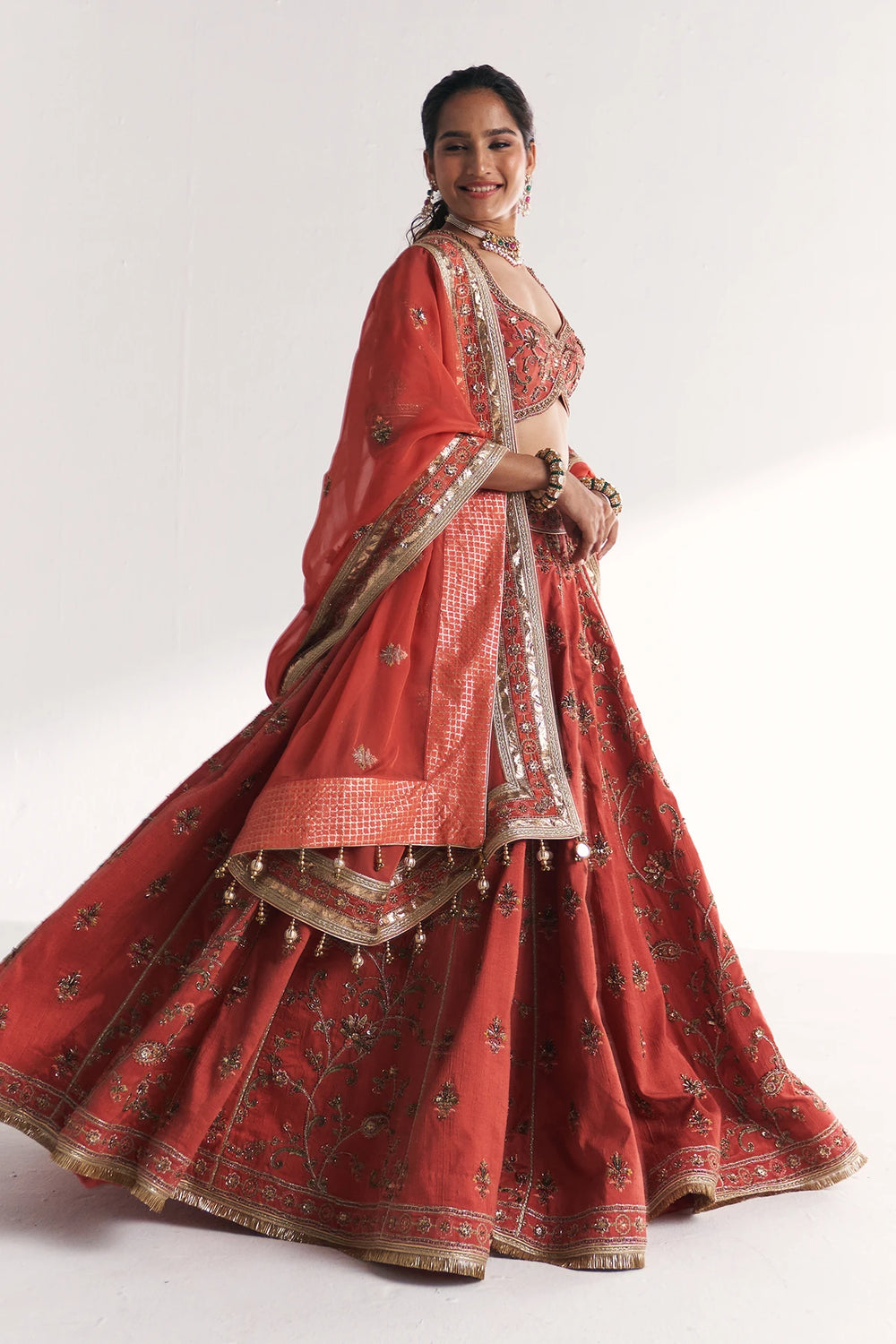 Woman wearing a traditional red embroidered Lehenga Set on a white background
