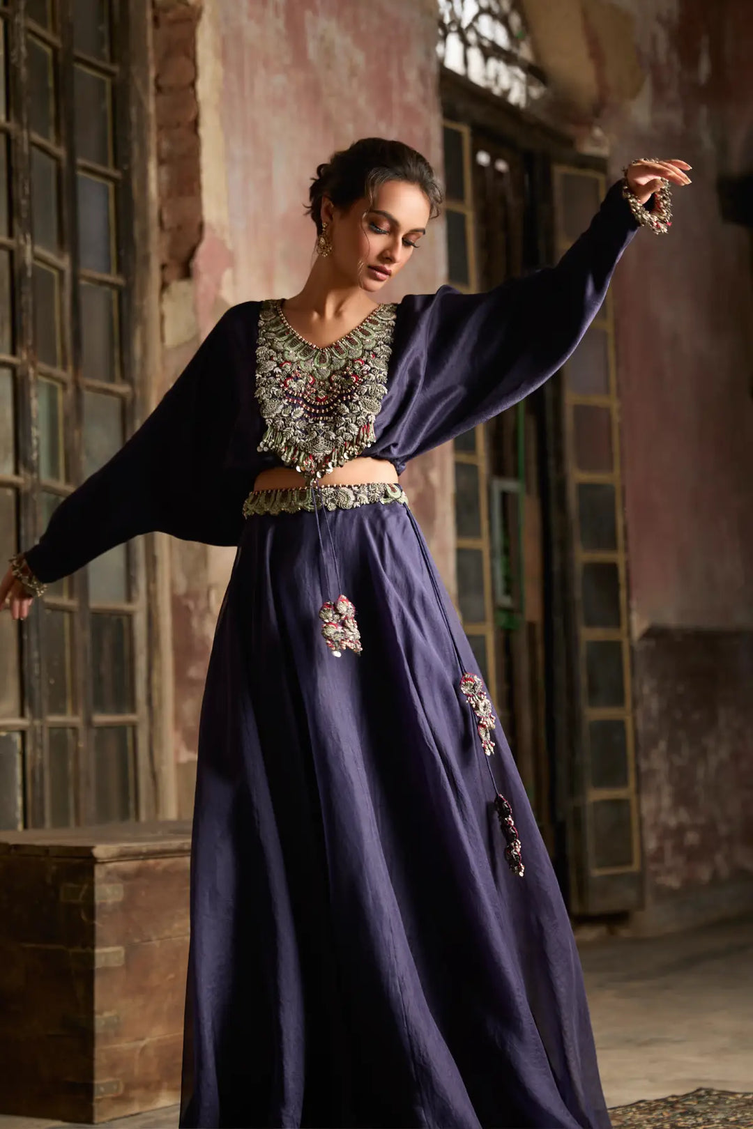 Woman in a traditional skirt with intricate designs in a rustic setting