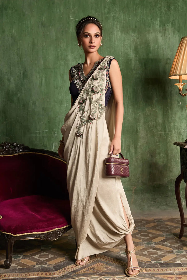 Woman in a skirt holding a handbag against a green wall.