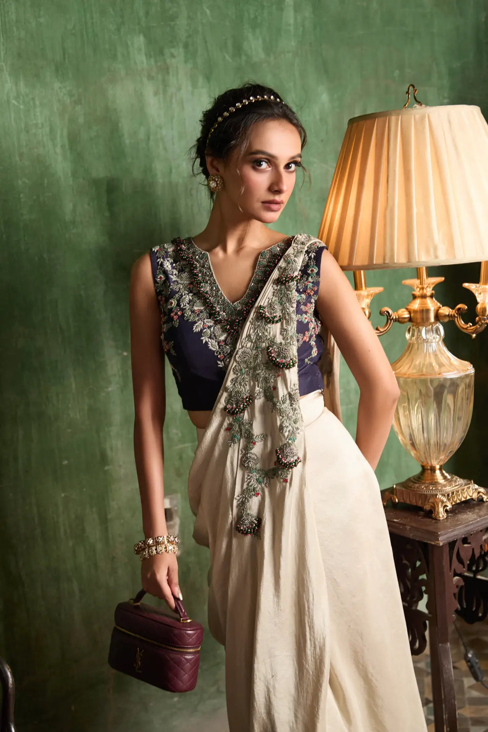 Woman in traditional skirt with a green wall and lamp in the background