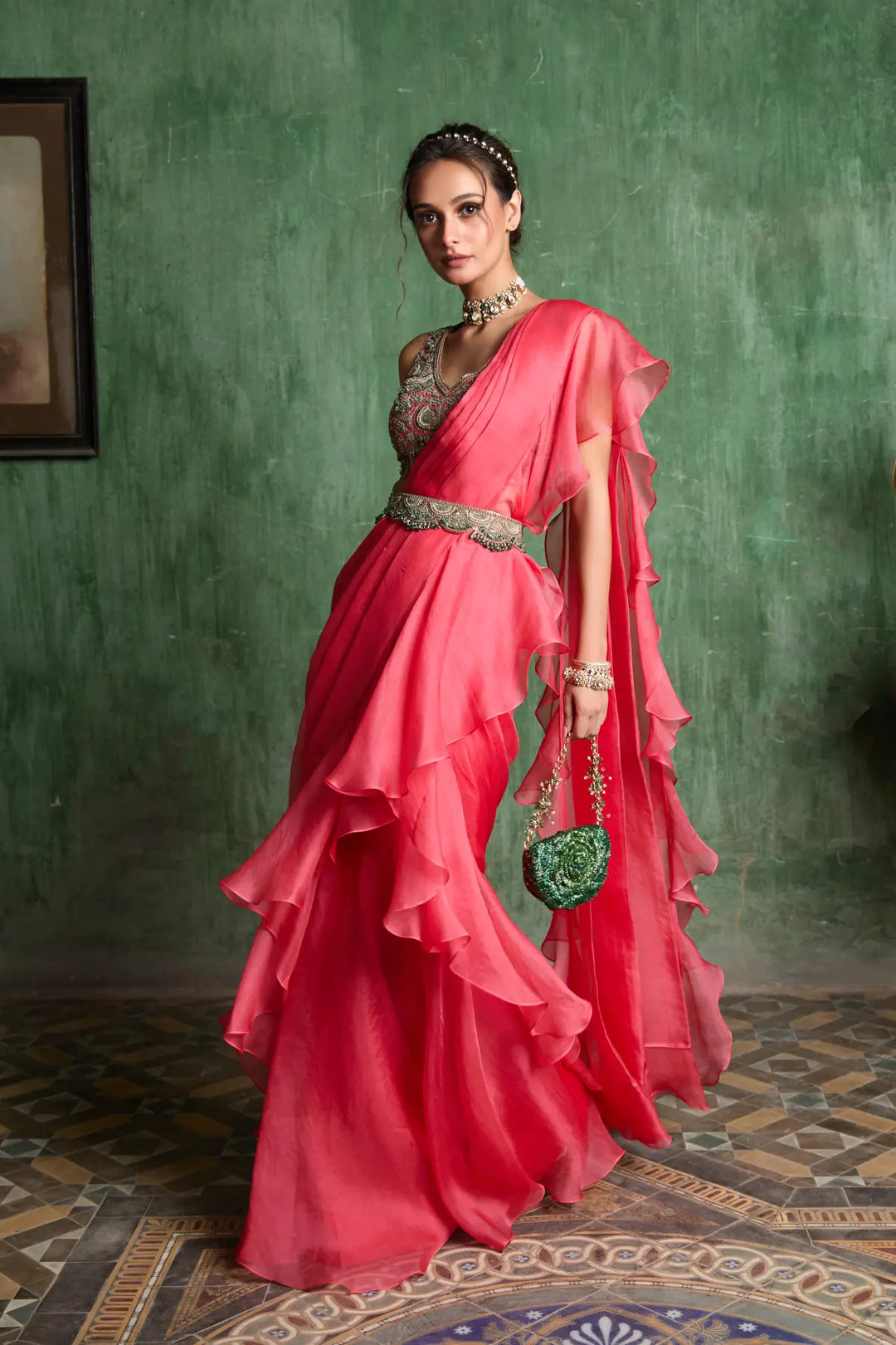 Woman in a pink saree with a green wall background