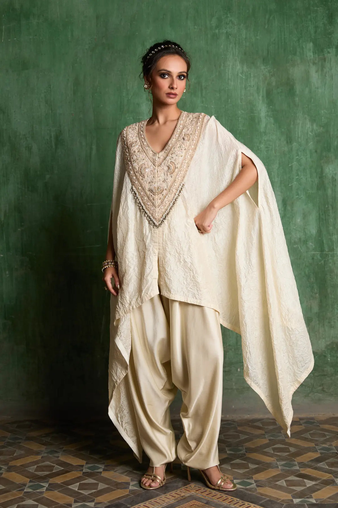 Woman wearing a traditional kaftan with a green textured wall background