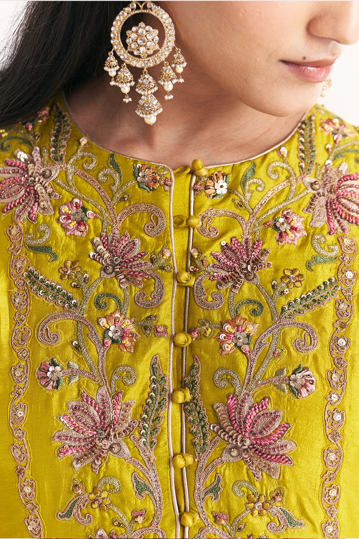 Close-up of a person wearing a yellow embroidered Anarkali with floral patterns and gold jewelry.