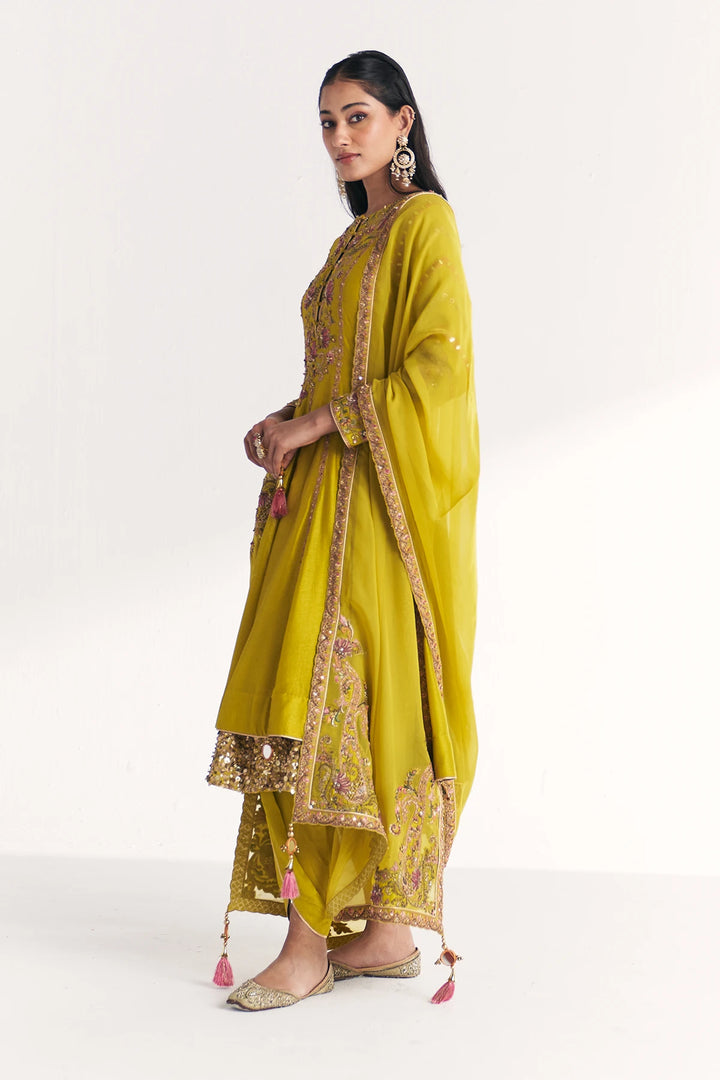 Woman wearing a yellow traditional Anarkali with gold embroidery on a white background