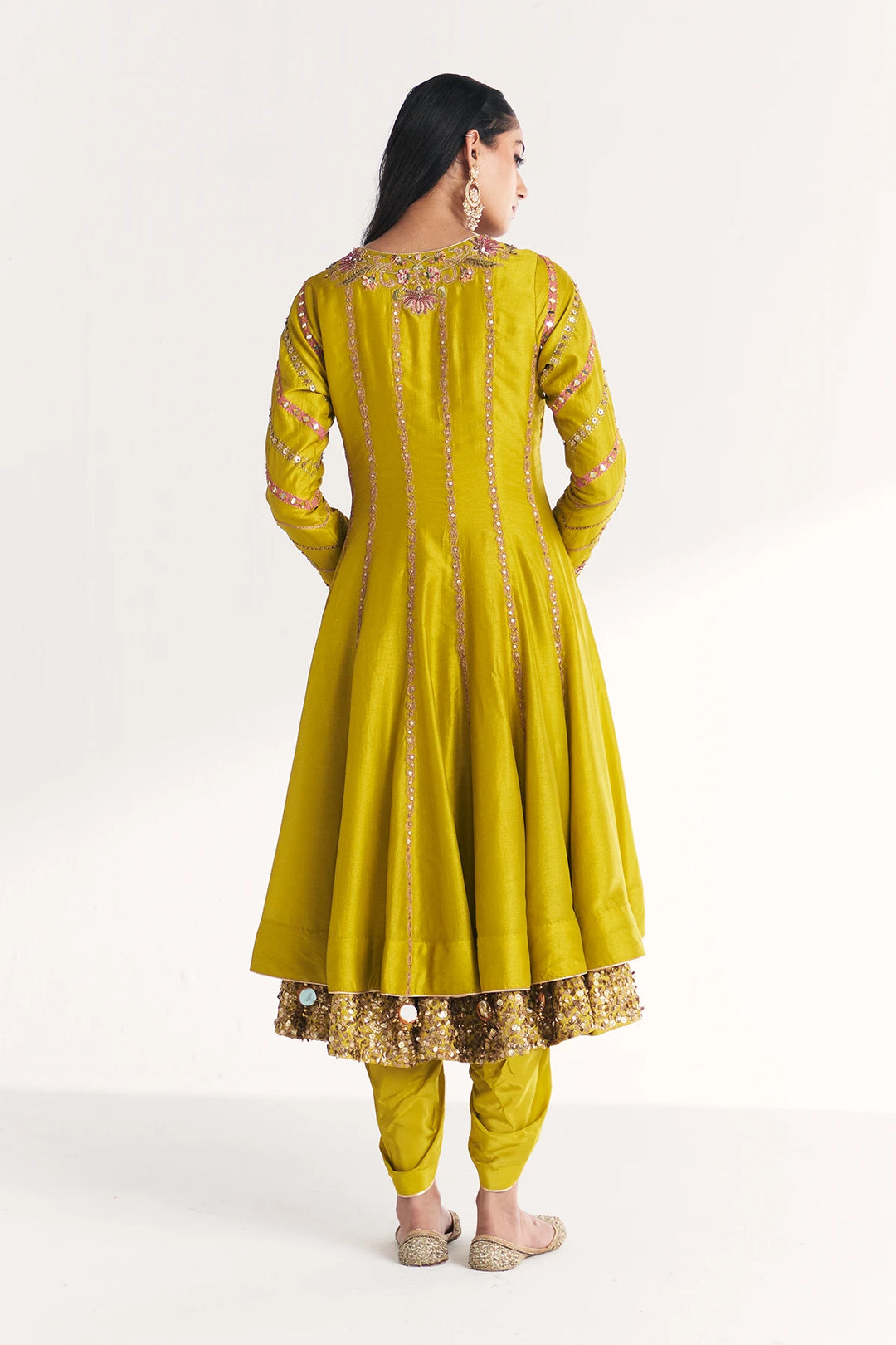 Woman wearing a yellow traditional Anarkali with intricate designs on a white background