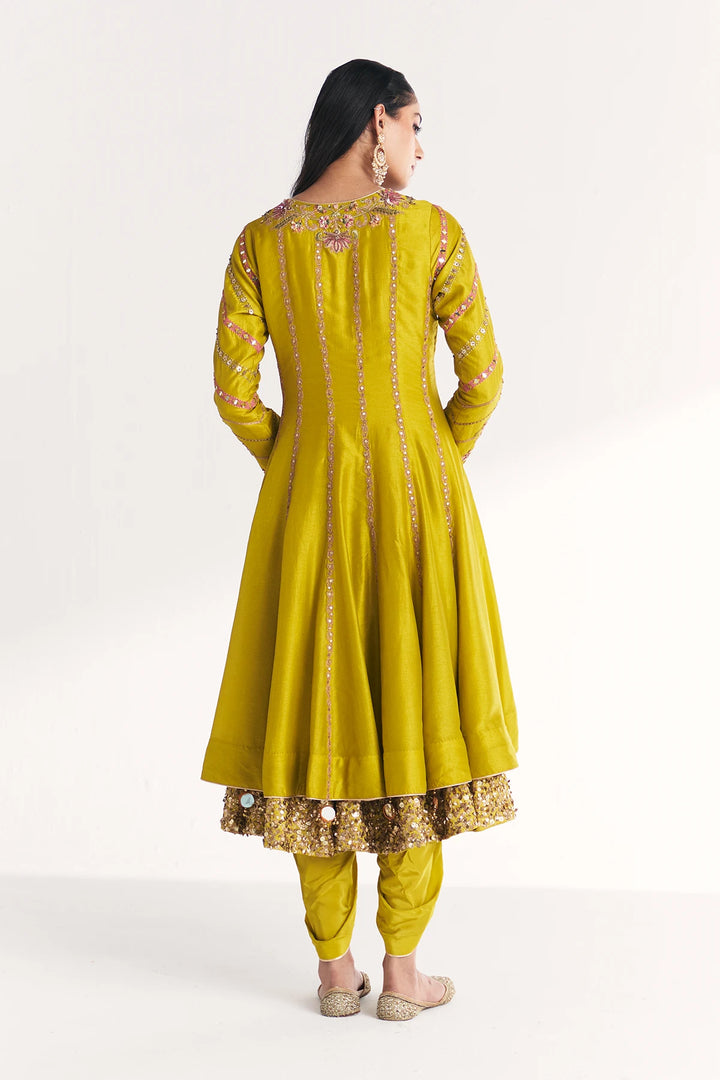Woman wearing a yellow traditional Anarkali with intricate designs on a white background