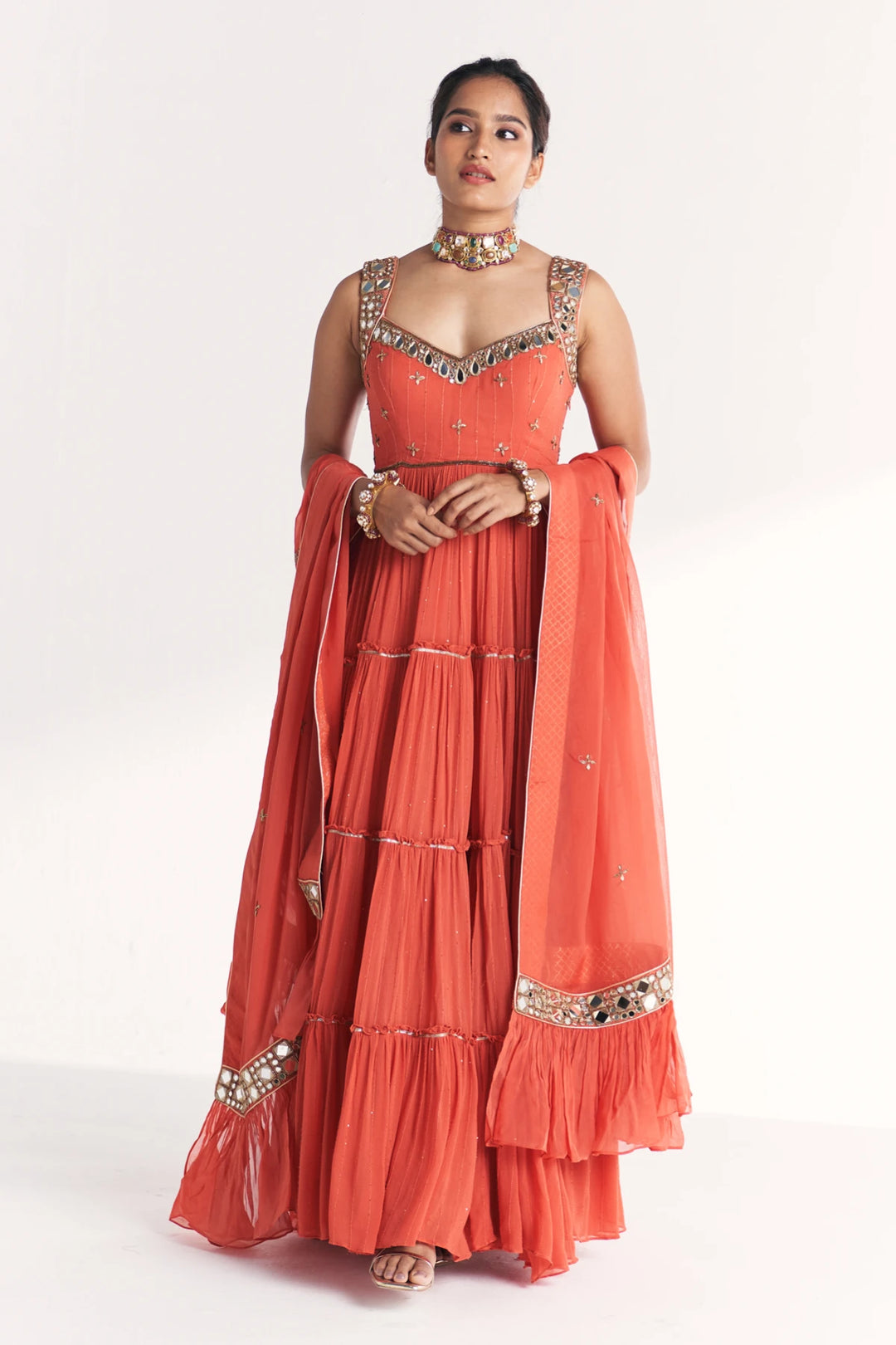 Woman wearing an orange traditional Anarkali with a matching dupatta on a white background