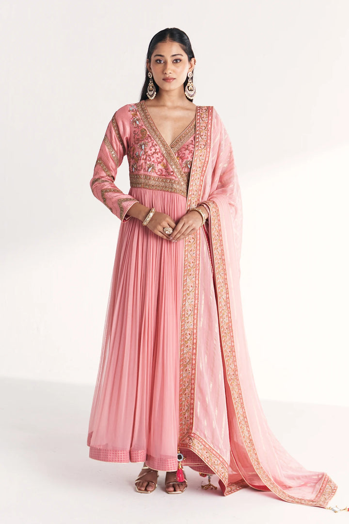 Woman wearing a pink traditional Anarkali with gold embroidery on a white background