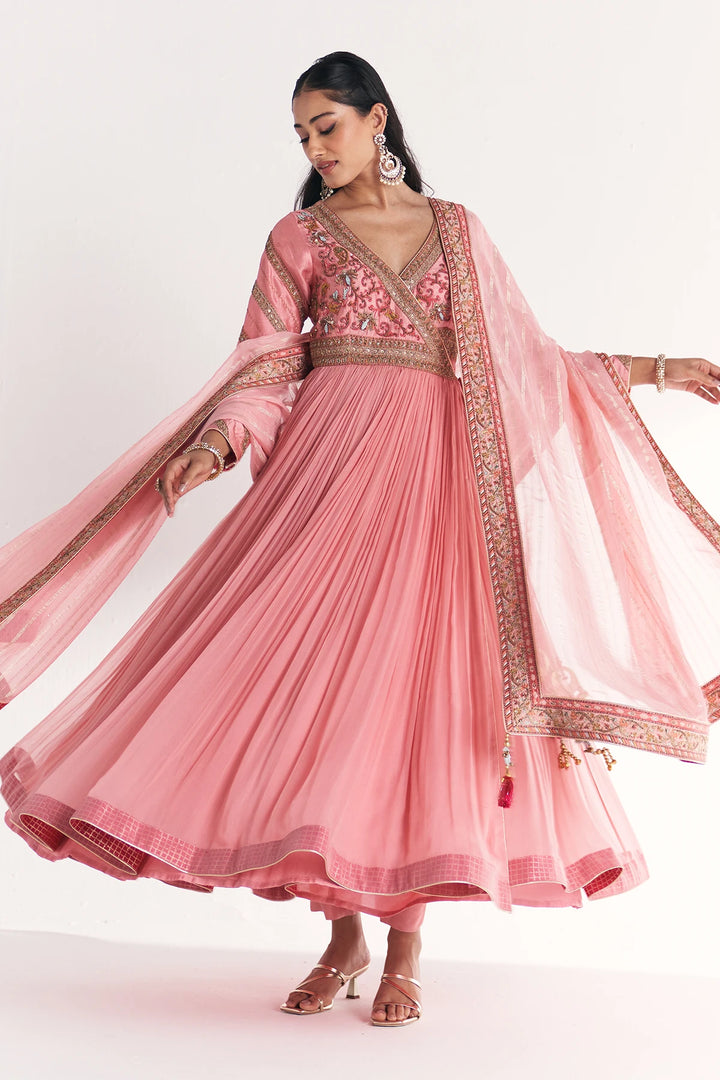Woman wearing a pink traditional Anarkali with embroidery on a white background