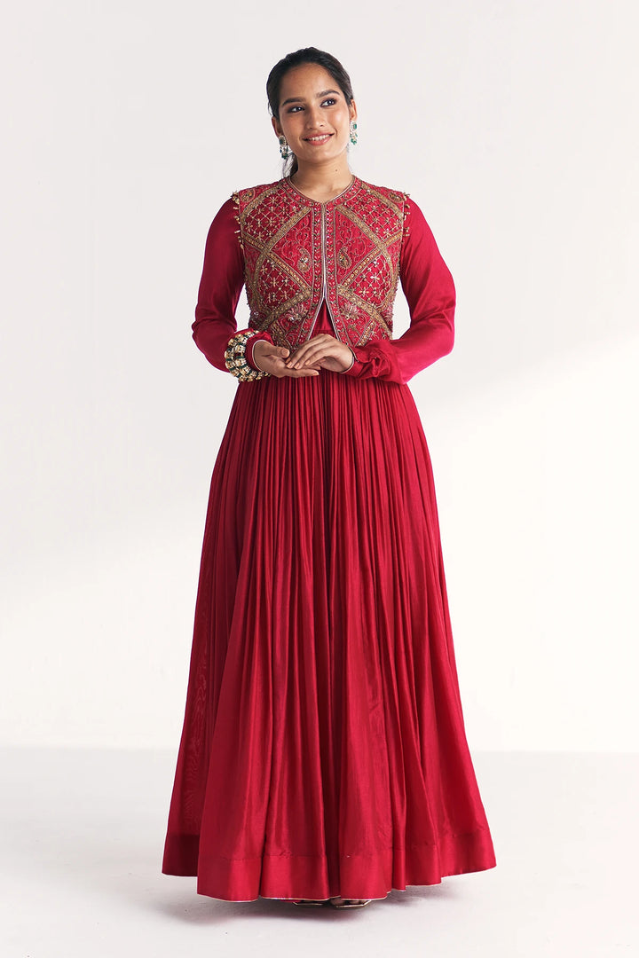 Woman wearing a red traditional Anarkali with intricate embroidery on a white background