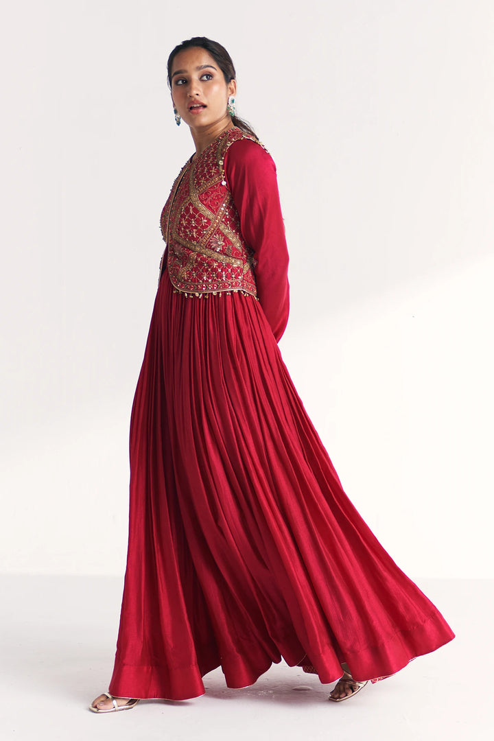 Woman wearing a red Anarkali with gold embroidery on a white background