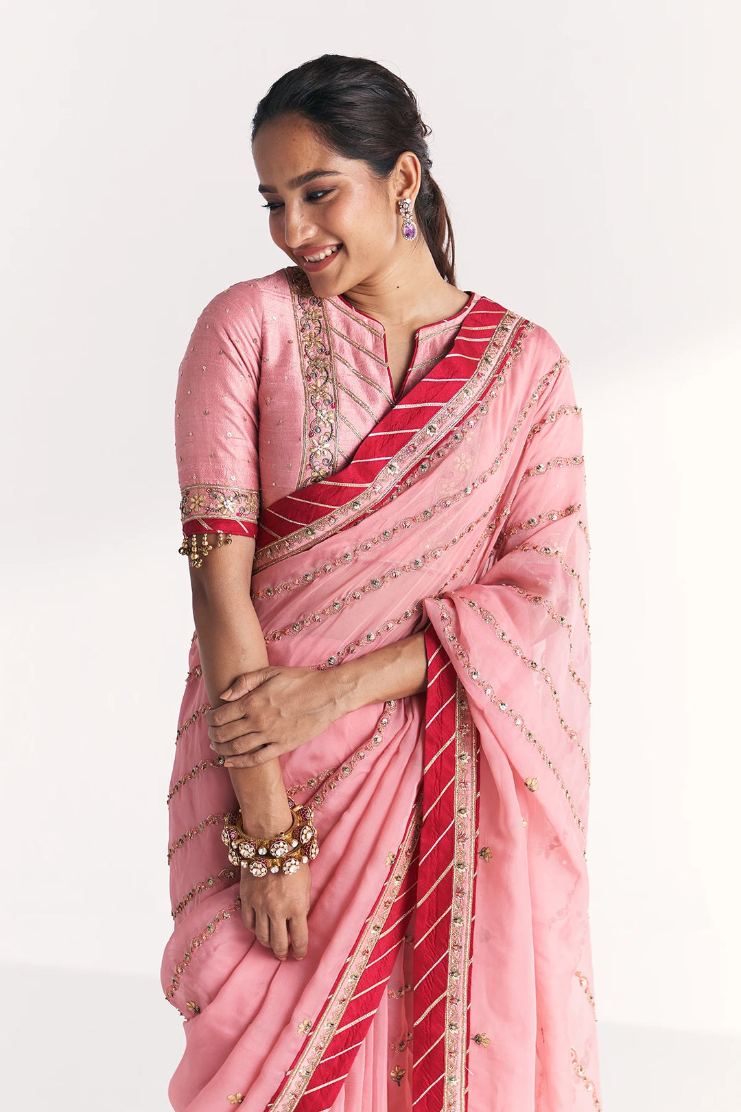 Woman wearing a pink saree with red stripes on a white background