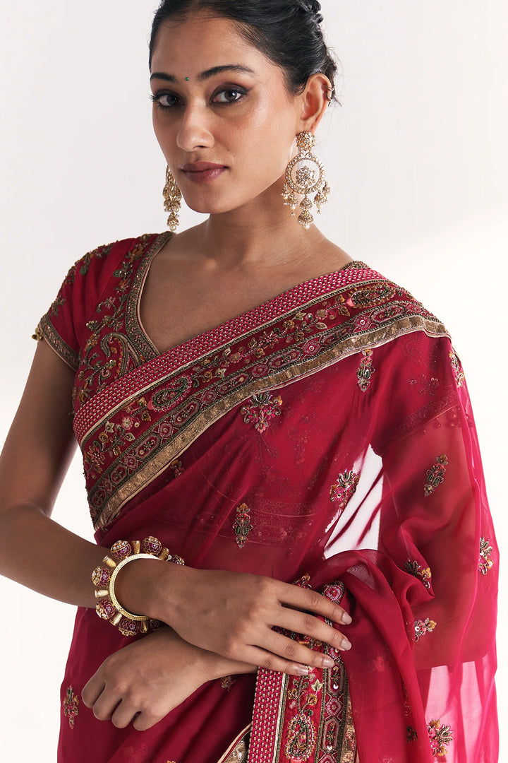 Woman wearing a red saree with intricate patterns on a white background