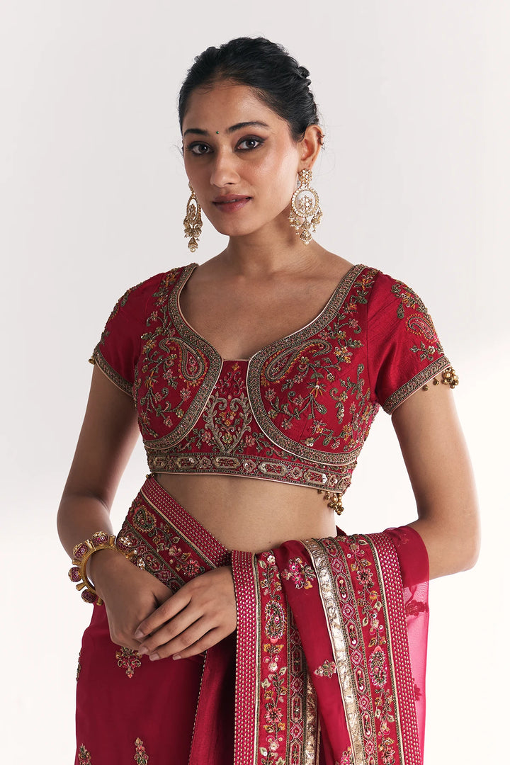 Woman wearing a red embroidered traditional Saree on a white background
