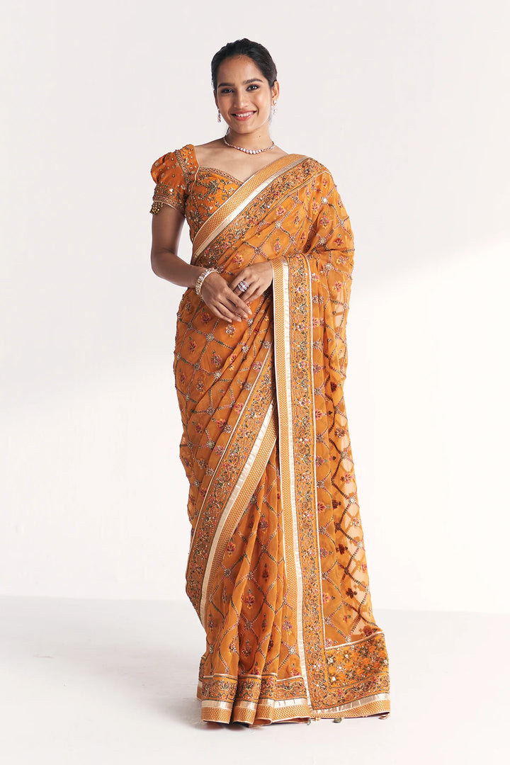 Woman wearing a traditional orange saree with a white background