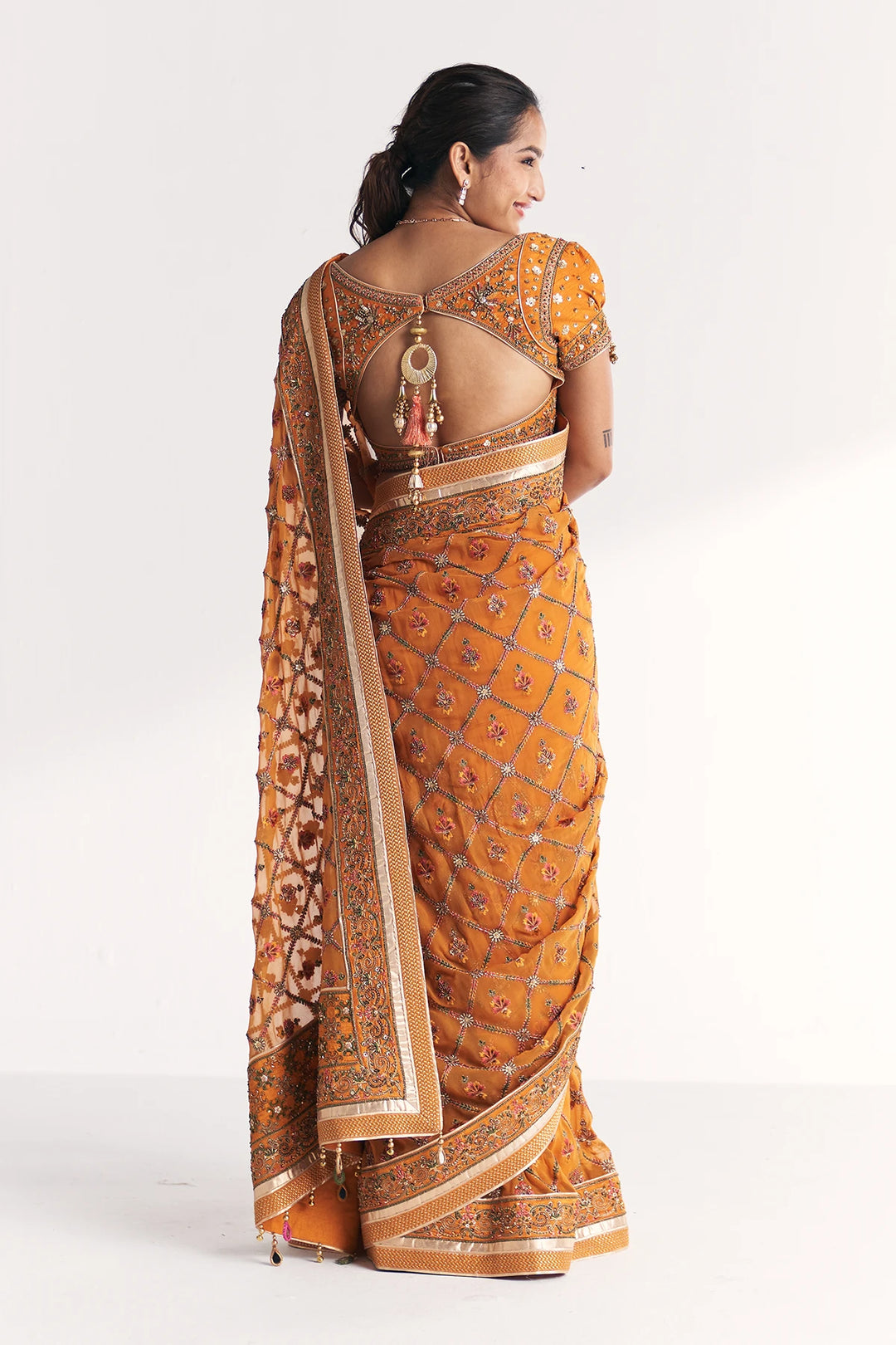 Woman wearing a mustard yellow saree with a white background