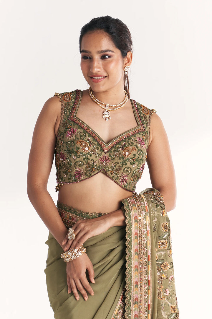 Woman wearing a traditional embroidered blouse and saree on a white background
