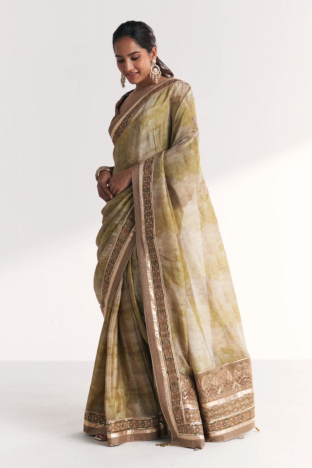 Woman wearing a green and beige saree with a white background