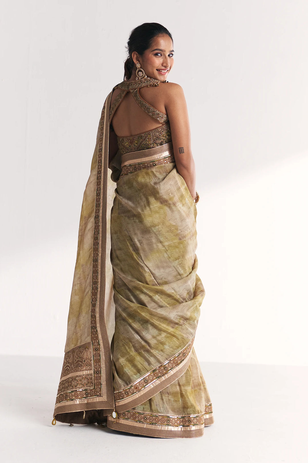 Woman wearing a traditional saree with a plain background