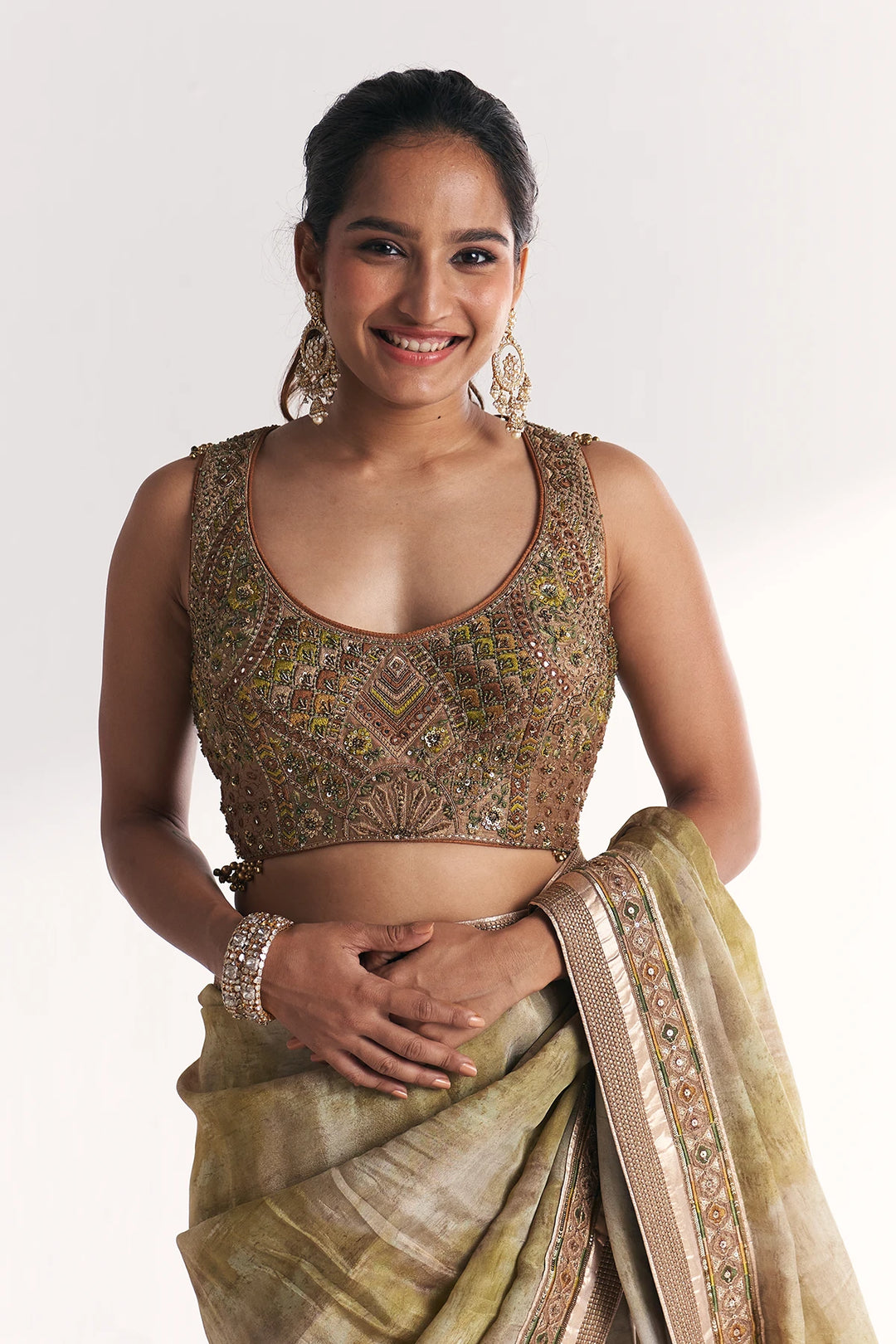 Woman wearing a traditional saree with intricate patterns on a white background