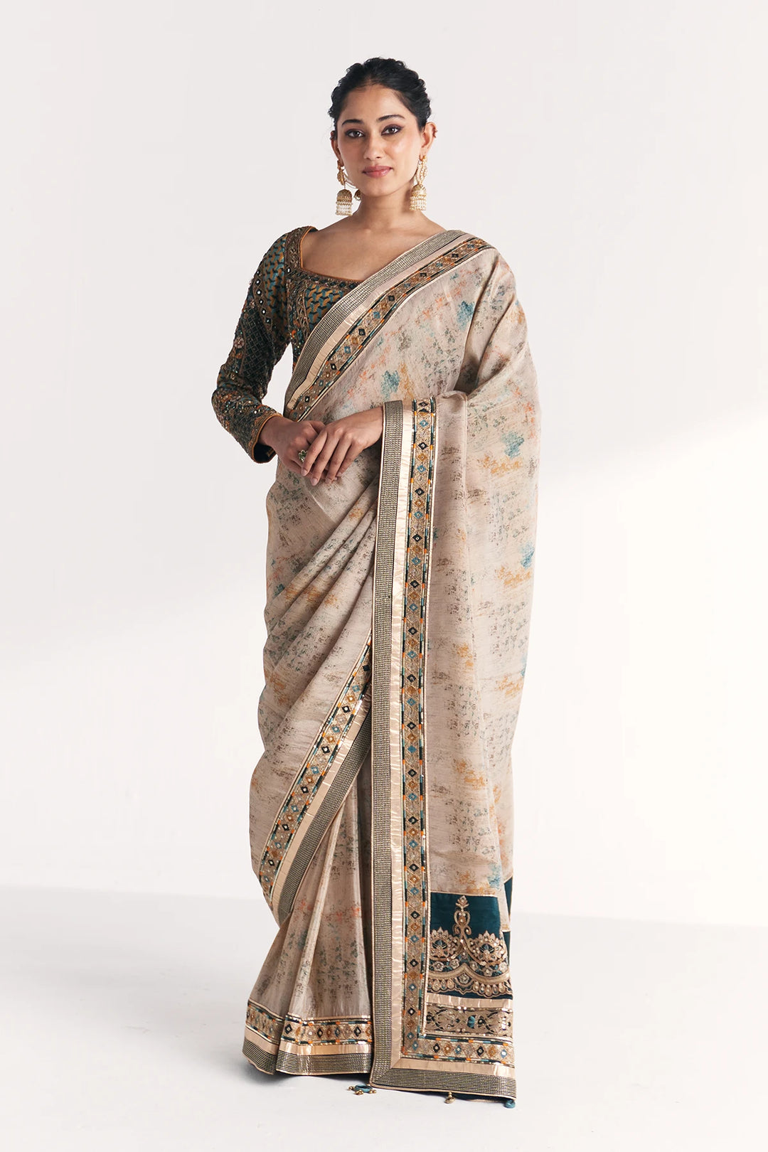 Woman wearing a traditional saree with intricate patterns on a white background