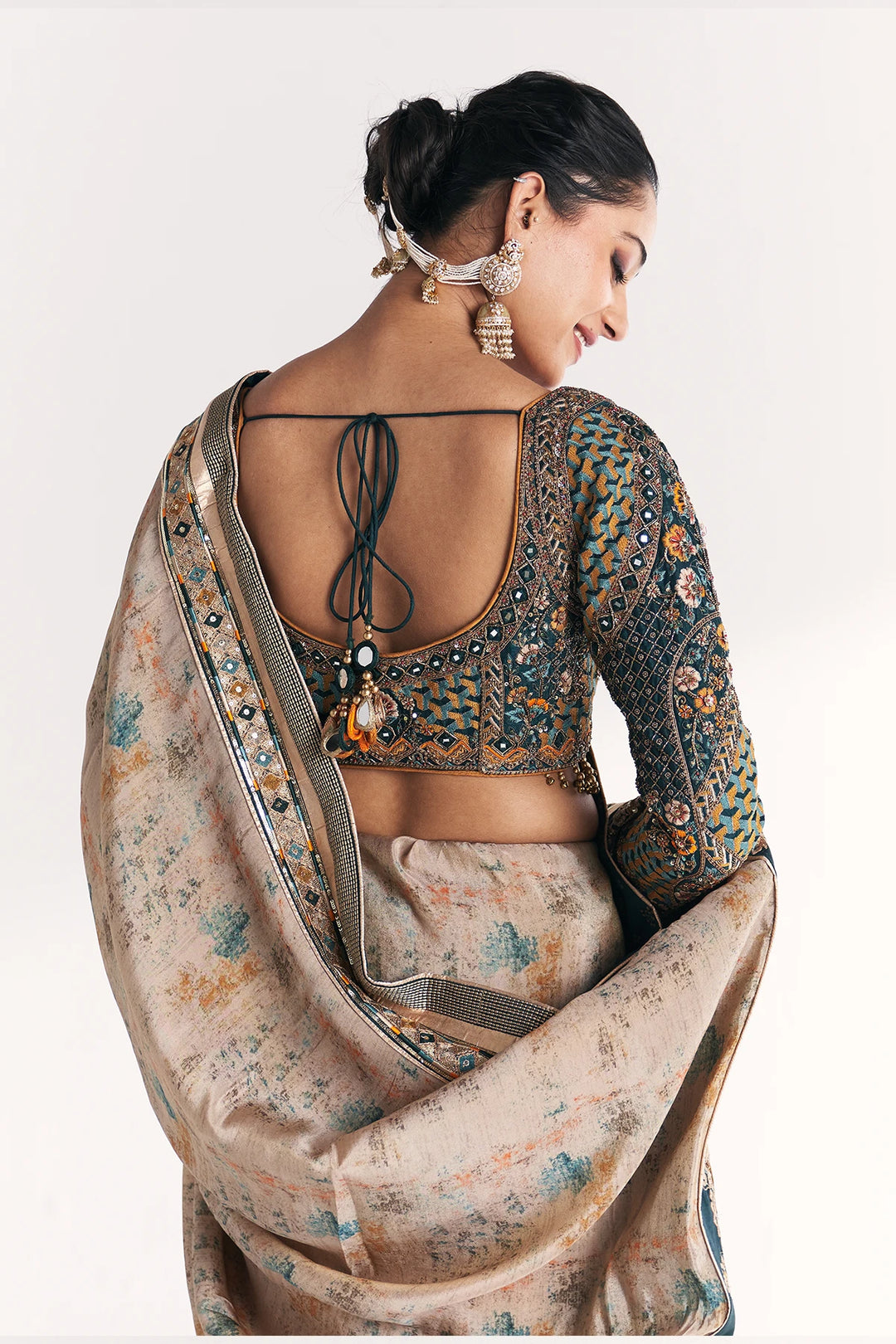 Woman wearing a traditional saree with intricate designs on a plain background