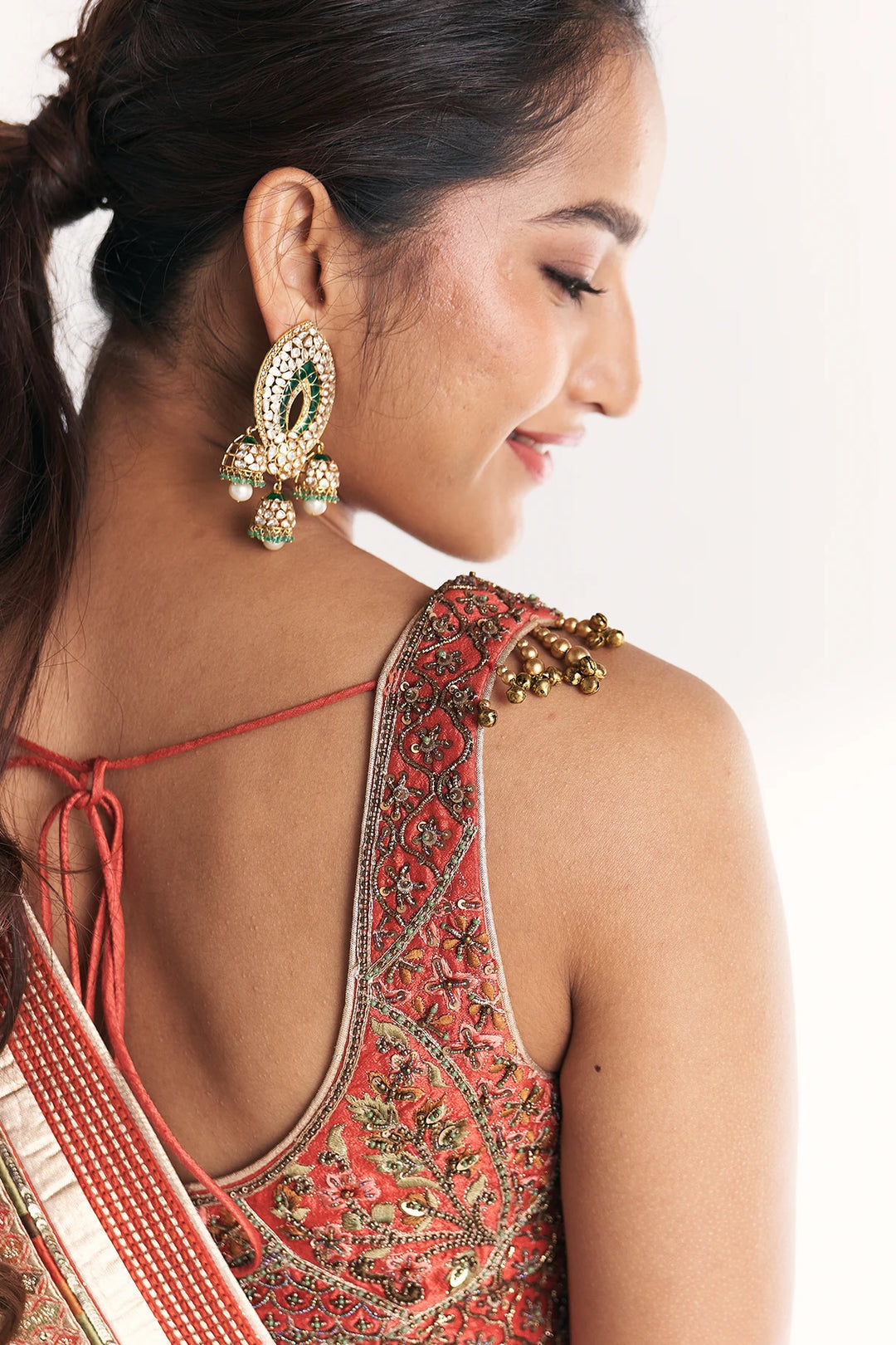 Woman wearing a red and gold traditional outfit with intricate designs on a white background
