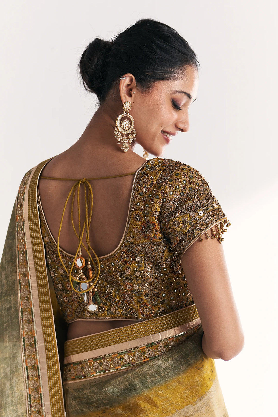 Woman wearing a traditional saree with intricate designs on a plain background