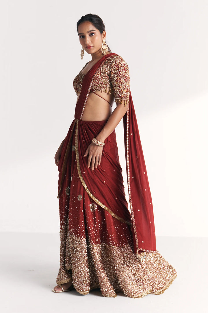 Woman wearing a traditional maroon Saree with gold embroidery on a white background