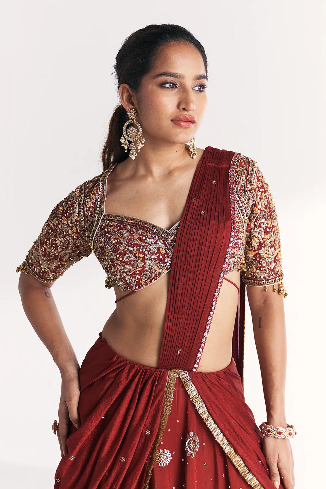 Woman wearing a red saree with gold embroidery on a white background