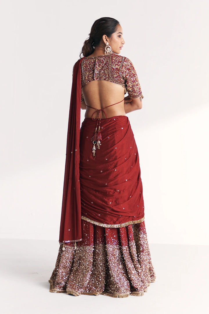Woman wearing a maroon saree with gold patterns on a white background