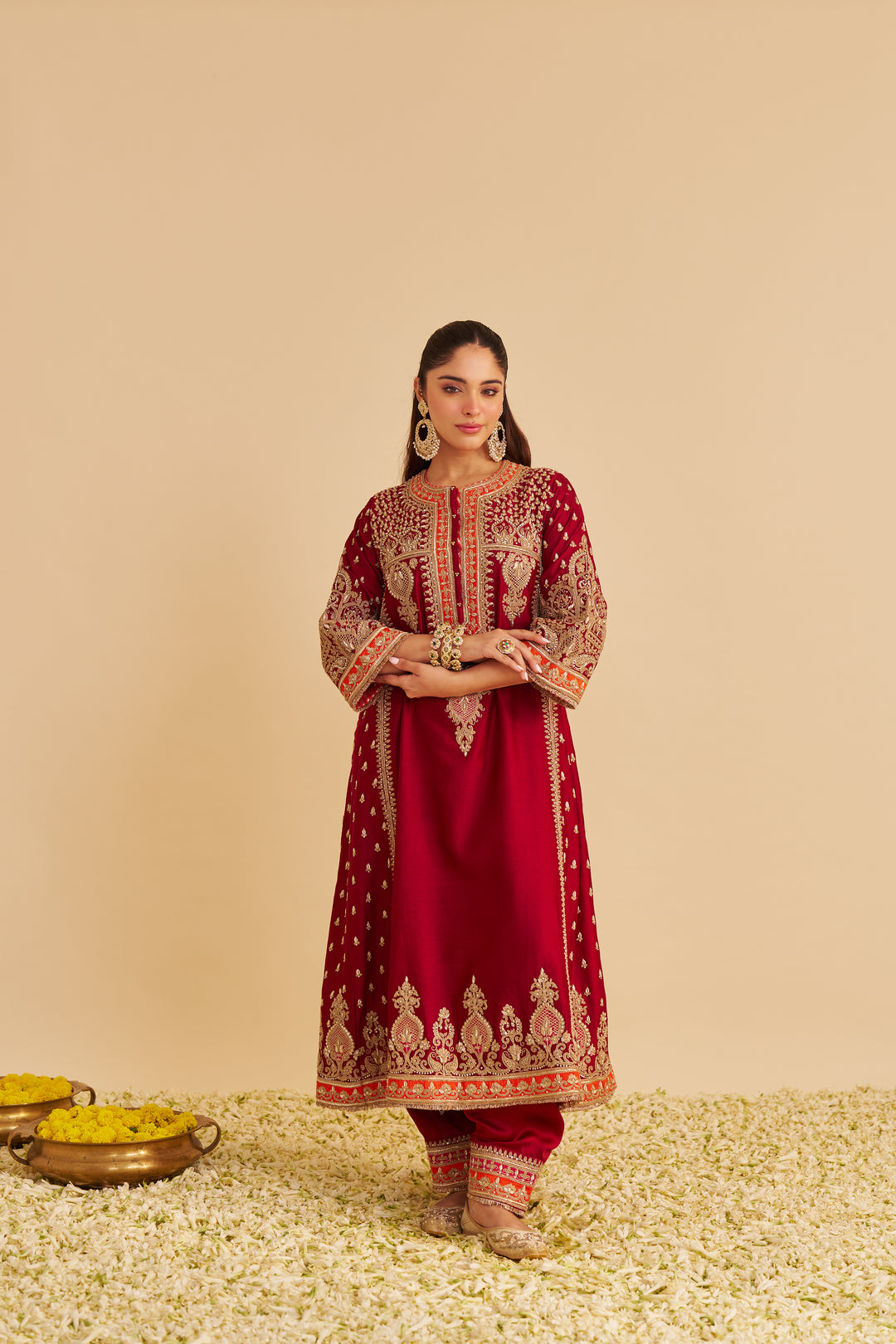 Woman wearing a red embroidered traditional Chauga on a beige background