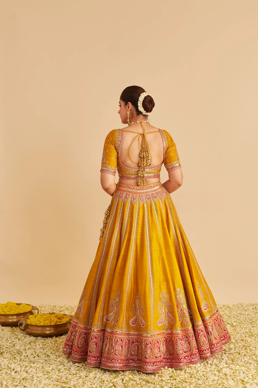 Yellow traditional lehenga with intricate designs on a beige background