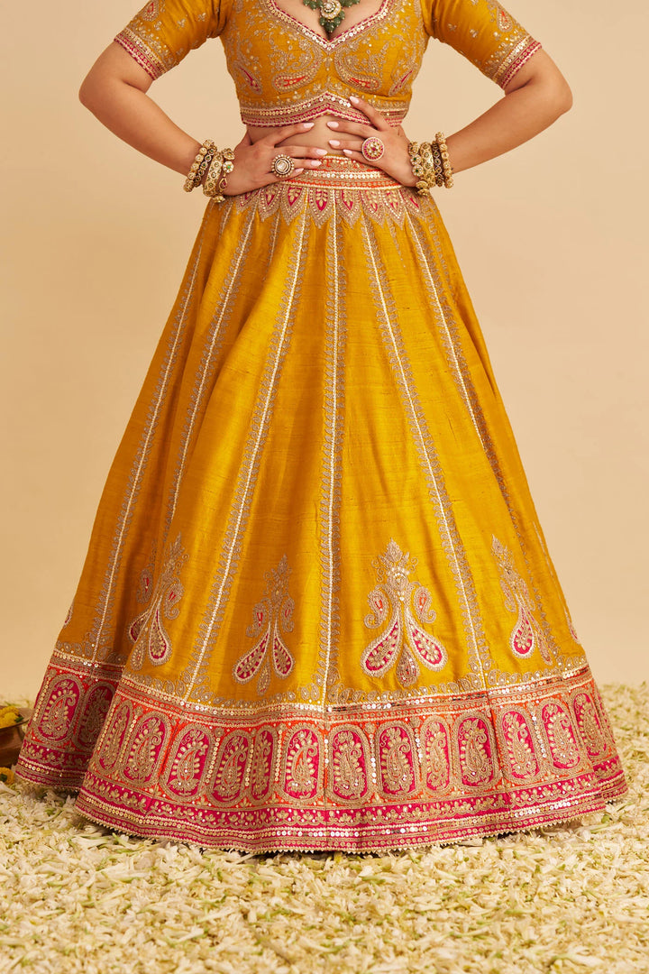 Yellow embroidered traditional lehenga on a beige background