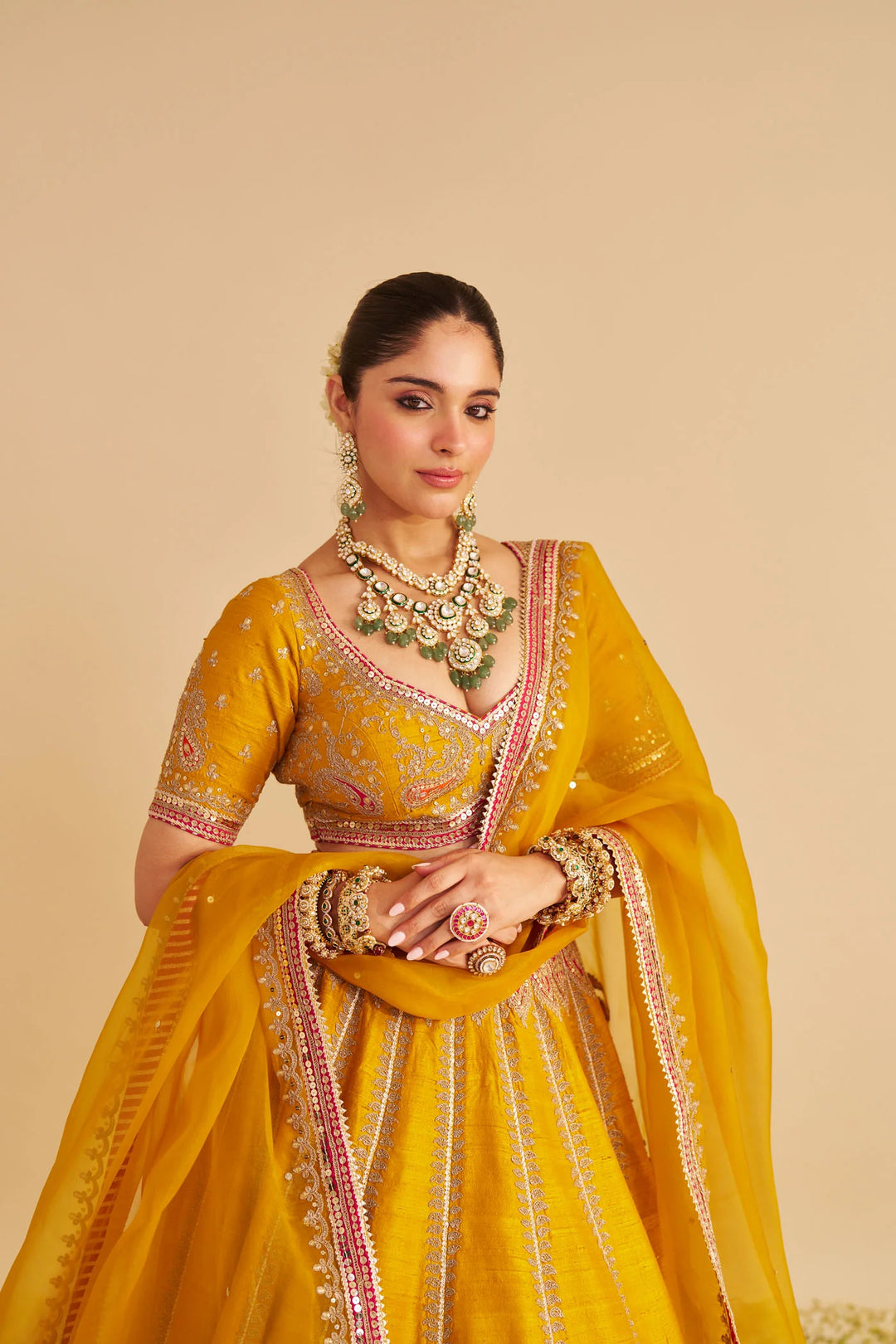 Woman in a yellow traditional lehenga with intricate designs on a beige background