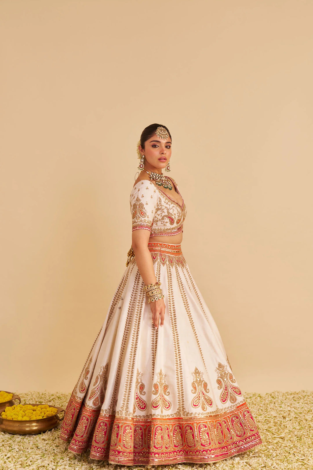 Woman wearing a traditional embroidered lehenga on a beige background