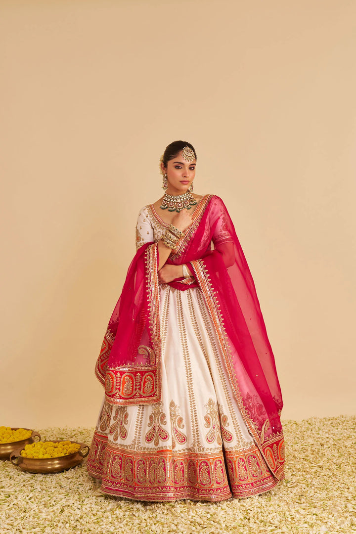 Traditional Indian bridal outfit with pink and white lehenga on a beige background
