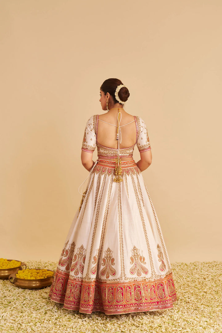 Woman wearing a traditional embroidered lehenga with a beige background