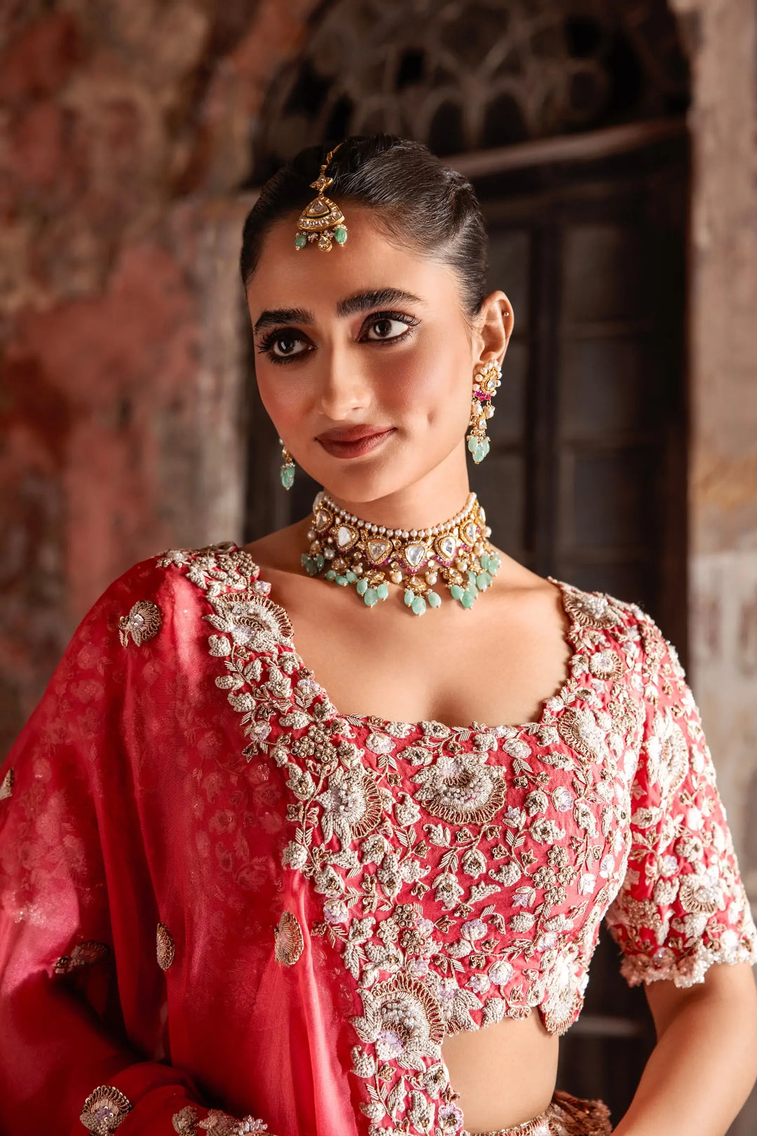 Woman in traditional red and white lehenga with jewellery against a warm-toned background