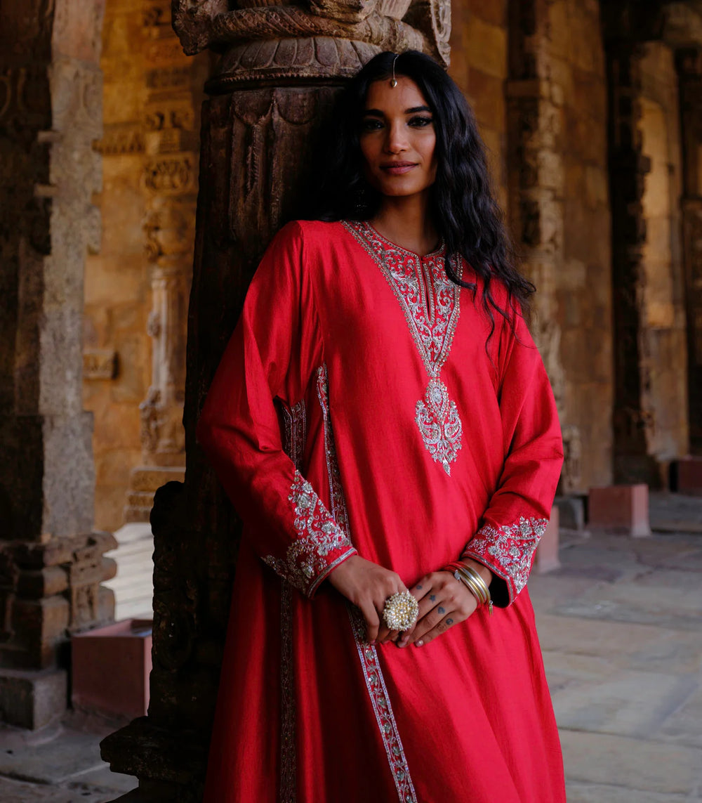 Woman in a red embroidered dress standing in an architectural setting
