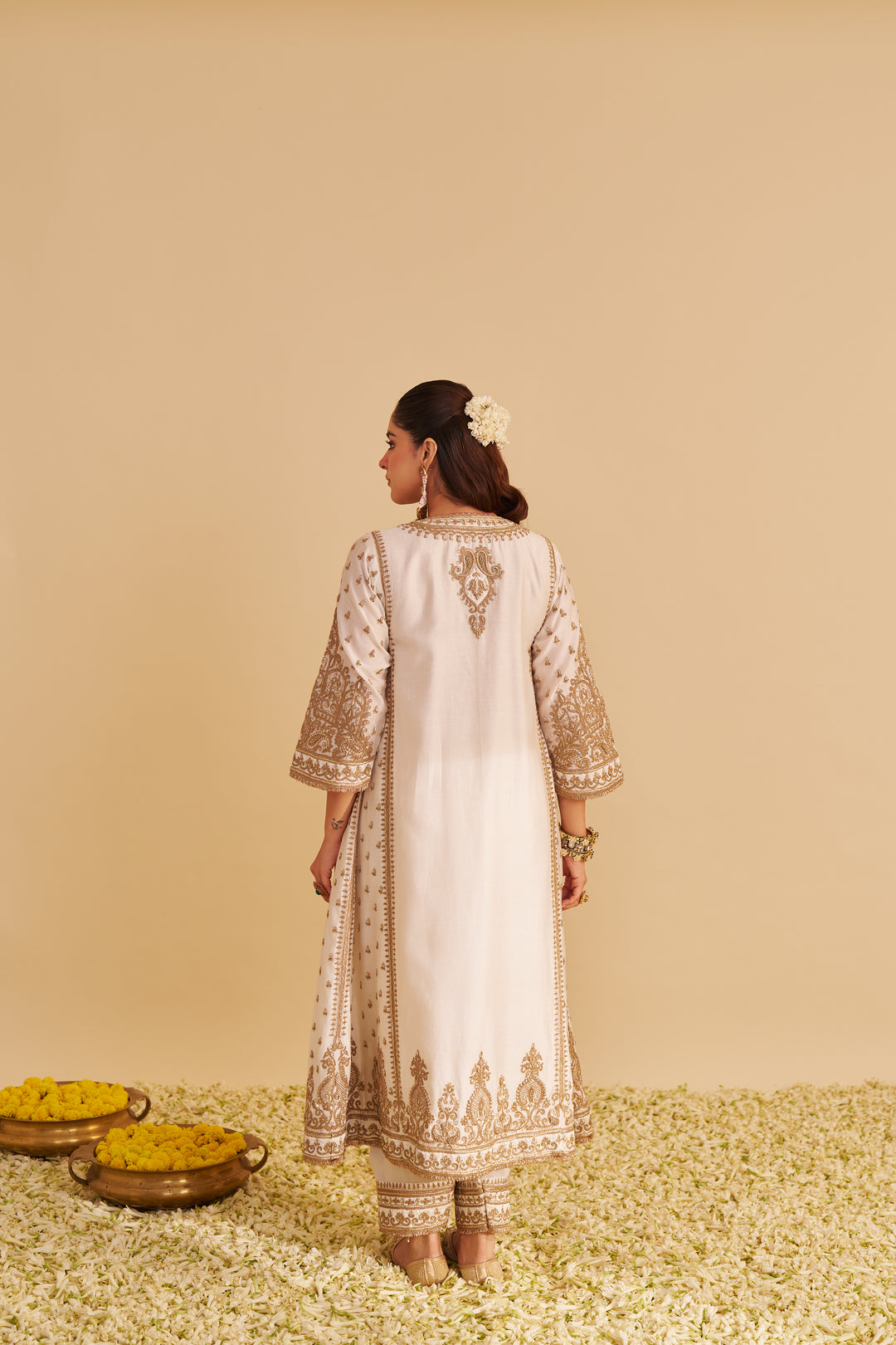 Woman wearing a white embroidered traditional Kurta with a beige background
