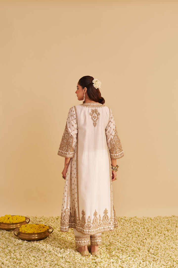 Woman wearing a white embroidered traditional Kurta with a beige background