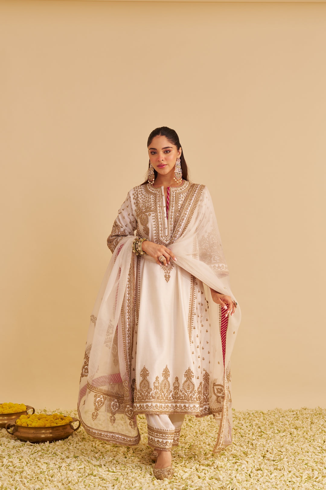 Woman in traditional embroidered outfit standing against a beige background
