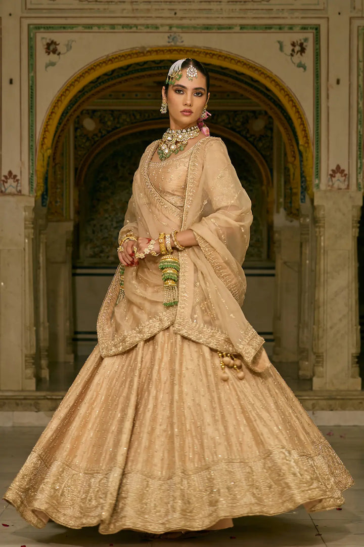 Woman in traditional beige embroidered lehenga with jewelry in an ornate setting