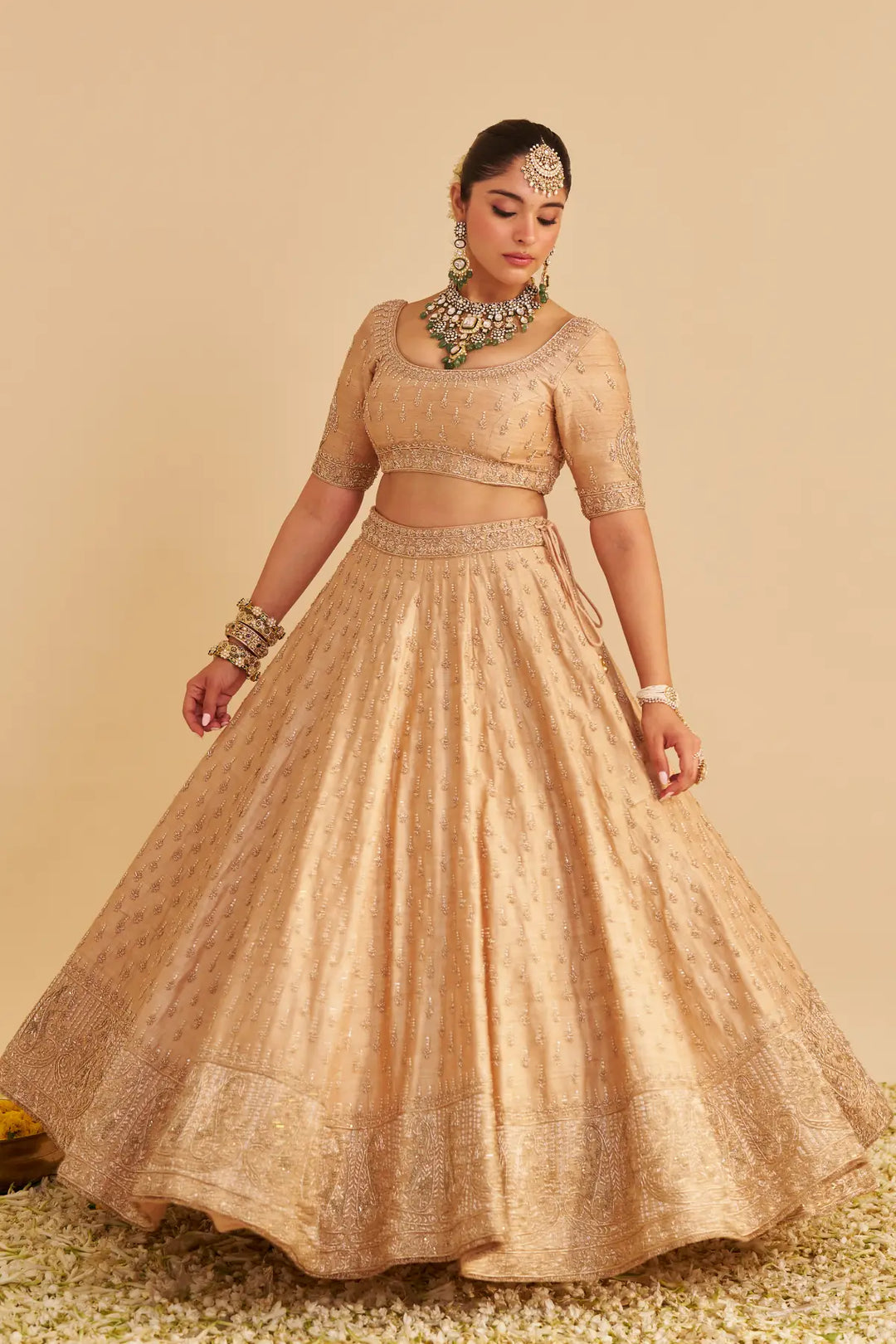 Woman wearing a traditional beige lehenga with jewellery on a beige background